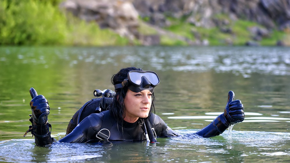 Taucherin im See mit Tauchmaske und Ausrüstung als Bild für Sicherheit, Selbstvertrauen und klares Feedback im Wasser.